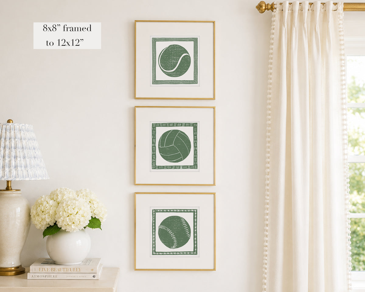 Trio of decorative grass green colored wall art with sports-themed prints on a white wall, next to a lamp and books.