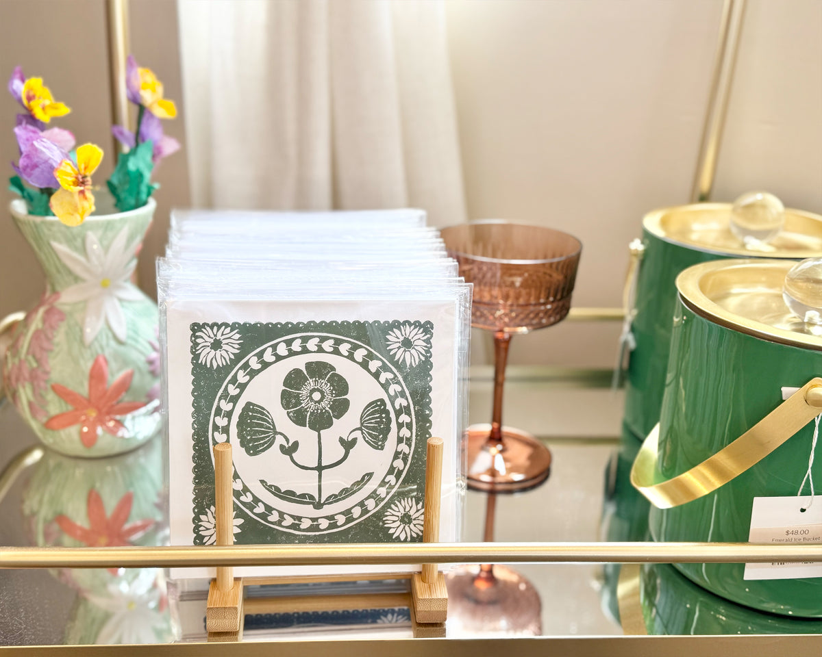 Stack of greeting cards with a decorative design on a glass table with candles and flowers.