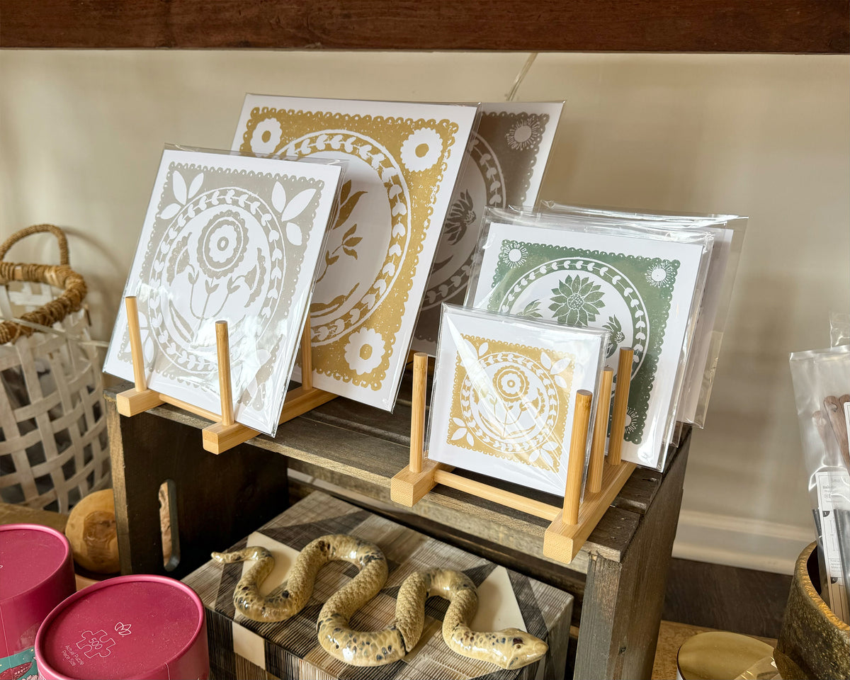 Decorative prints on stands with a wooden shelf in the background