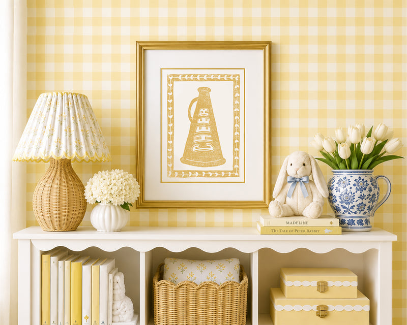 Framed mustard yellow cheer megaphone in a styled yellow and white bedroom