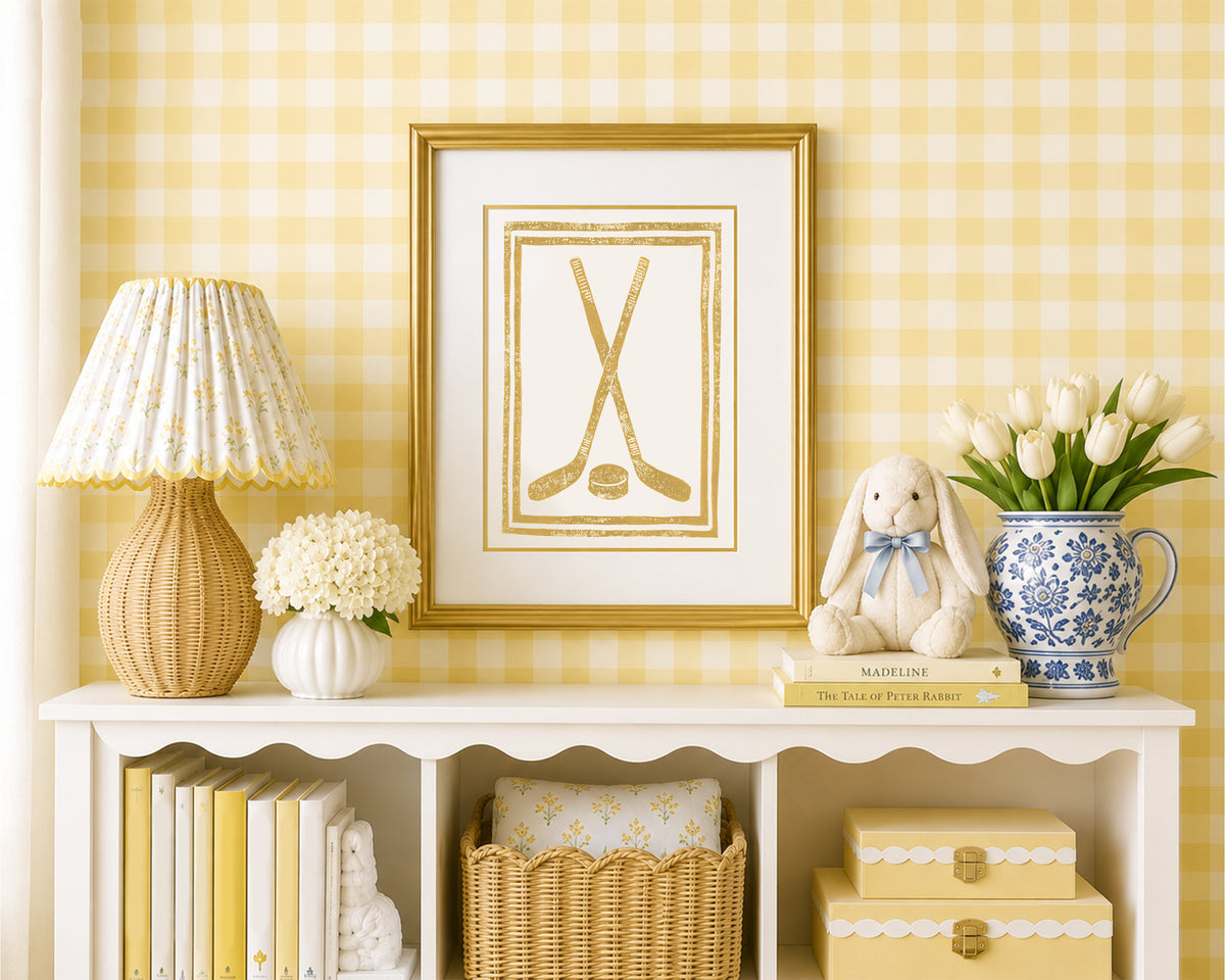 Framed mustard yellow crossed hockey sticks and puck in a styled yellow and white bedroom