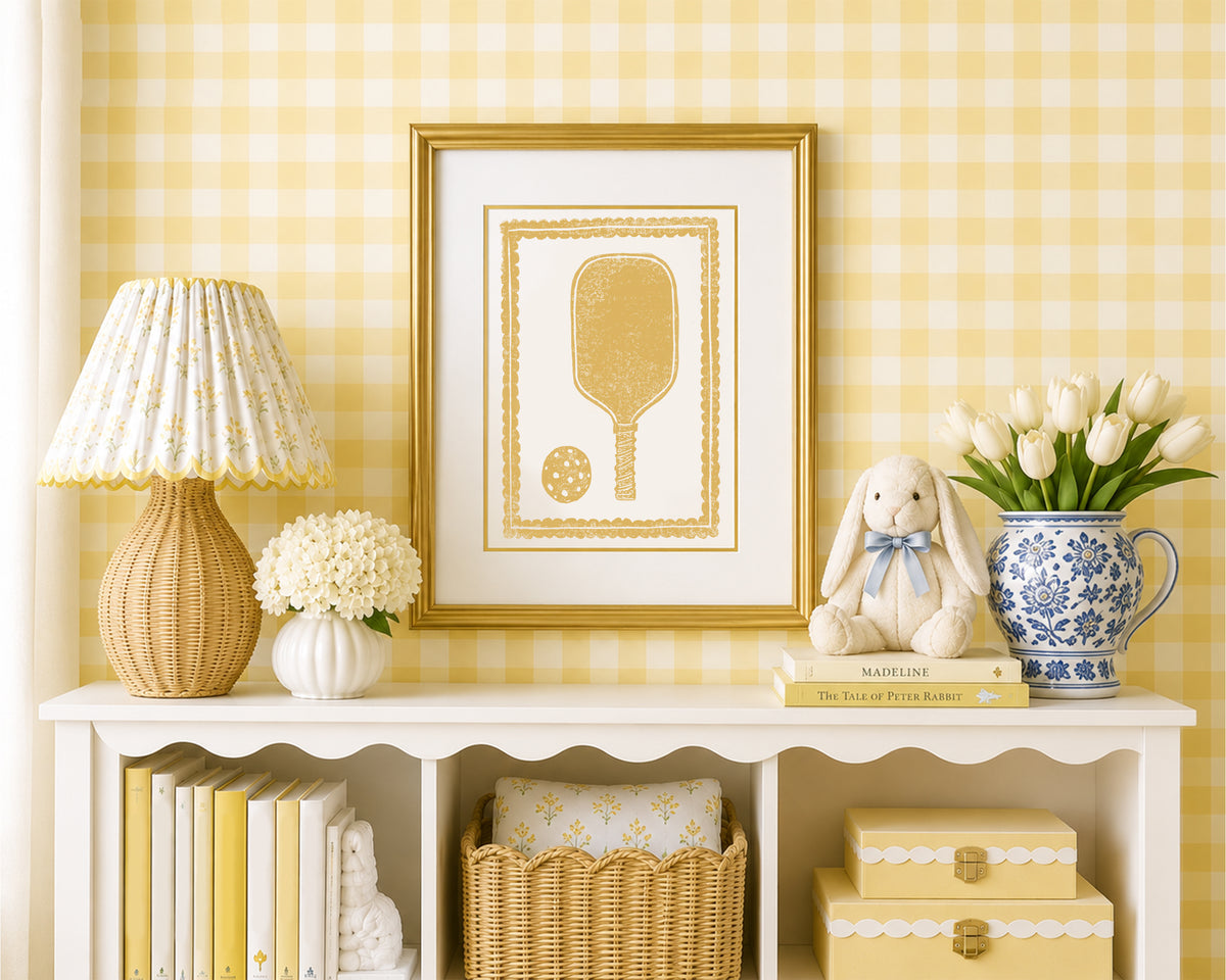 Framed mustard yellow pickleball racket in a styled yellow and white bedroom