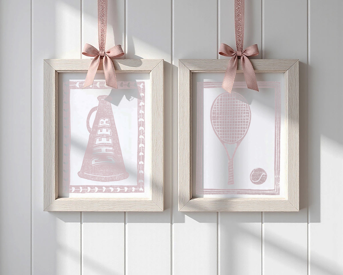 Framed art prints of mauve pink art prints hanging from bows on a white wall