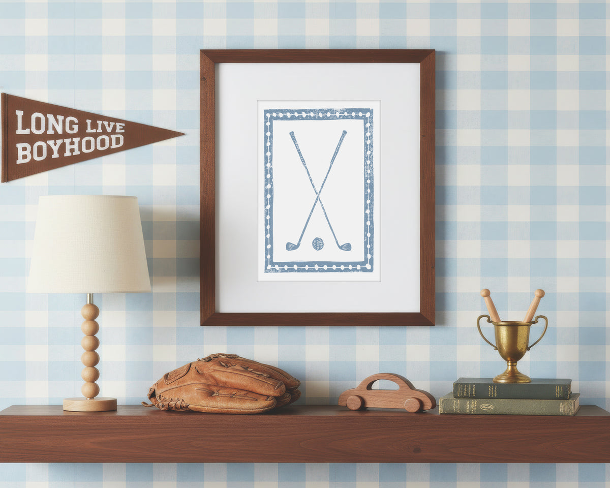 Framed cornflower blue and white golf club artwork on a shelf with decorative items against a checkered wall.