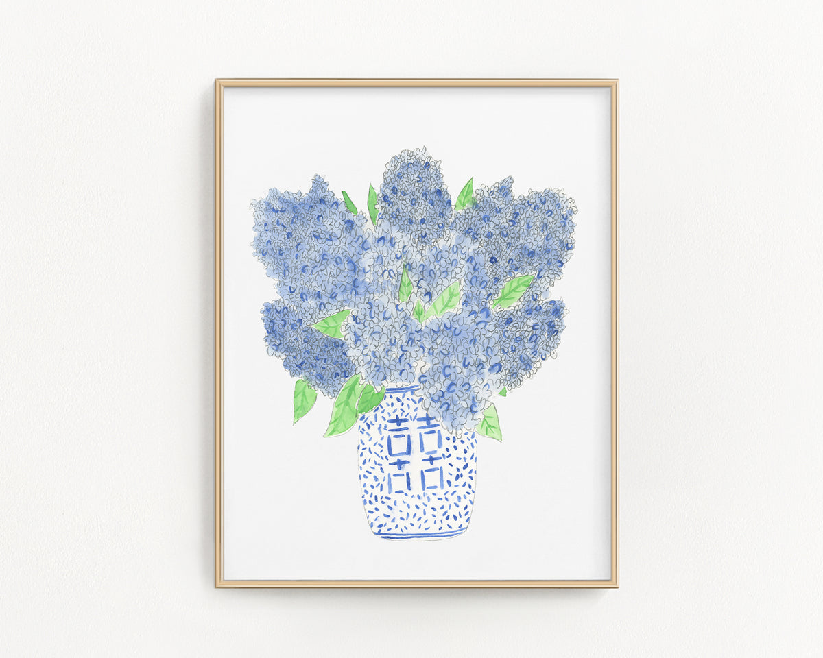 Framed artwork of blue flowers in a vase on a white wall
