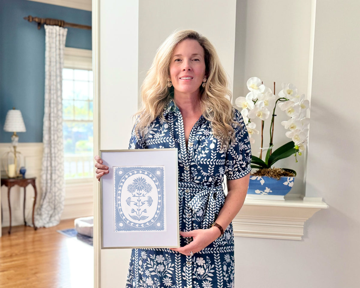 Woman holding a framed picture in a room with decor elements.
