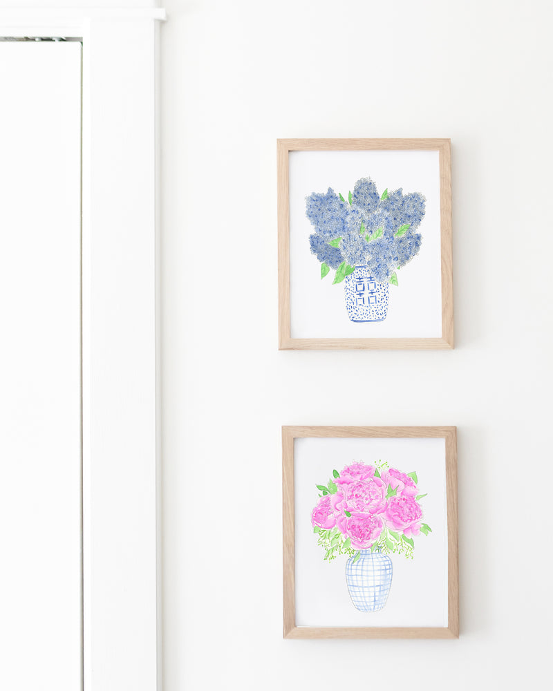 Two framed prints of floral designs on a white wall.